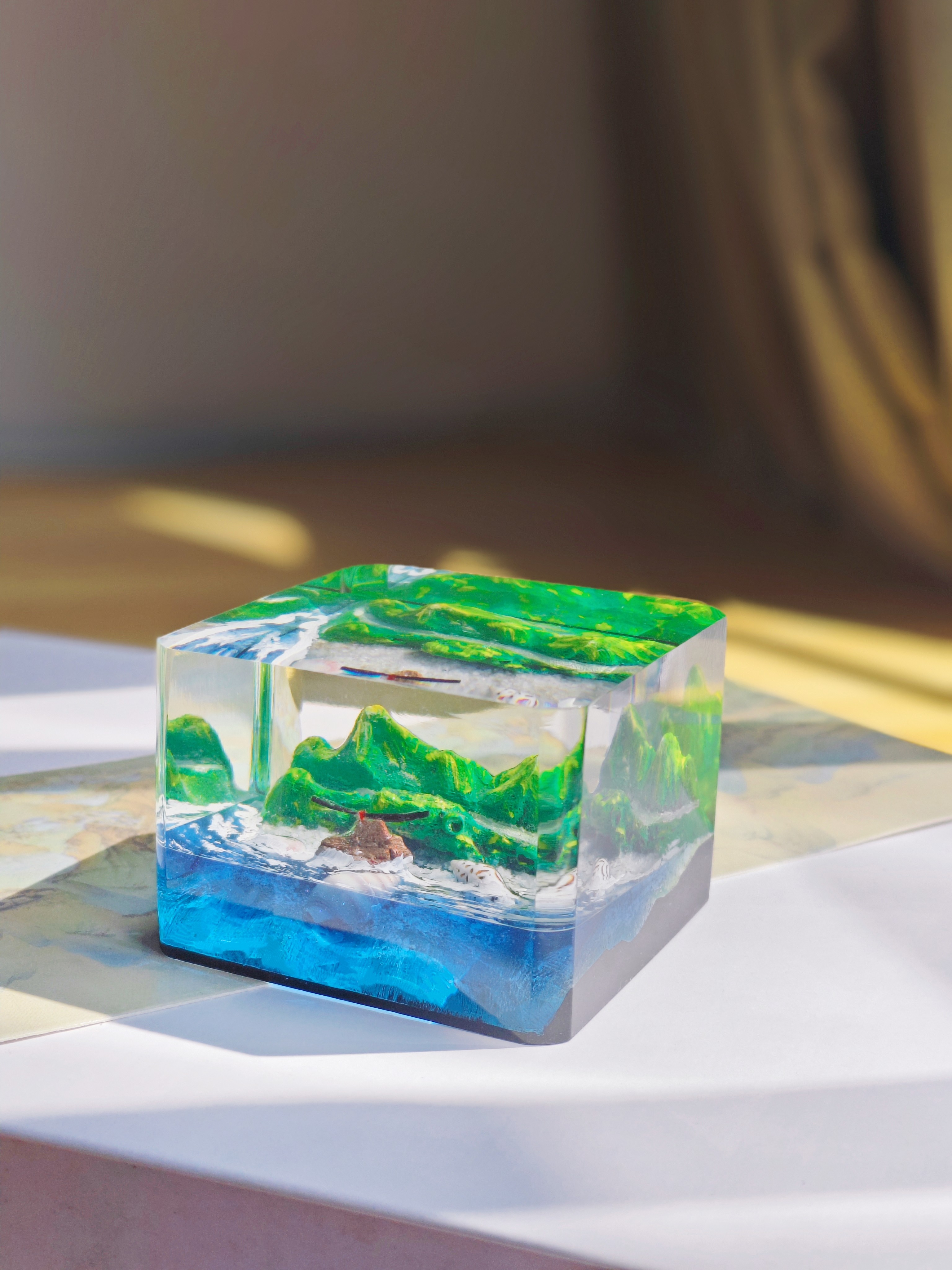 Layered resin ornament in green and blue tones resembling mountains and sea
